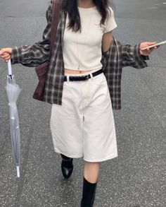 Person in a plaid shirt, white shorts, and black boots walking on a street