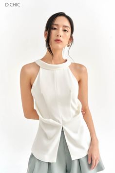 Woman in a white sleeveless top and light green pants in a studio
