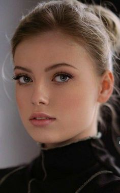 Close-up portrait of a woman with blonde hair in an updo and blue eyes