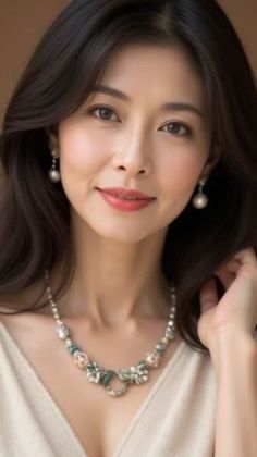 Woman with long dark hair wearing pearl earrings and a decorative necklace