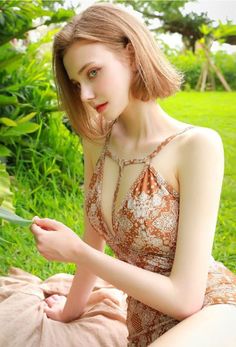 Woman in a patterned swimsuit sitting on a blanket outdoors