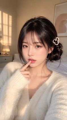Woman in a white sweater with a heart hair clip in soft indoor lighting