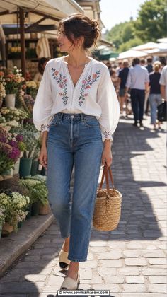 Woman in an embroidered blouse and jeans walking through a flower market