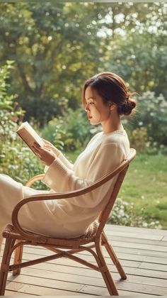 Woman with bun hair reading a book in a wicker chair outdoors