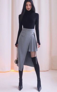 Woman with long black hair wearing a turtleneck and asymmetrical skirt