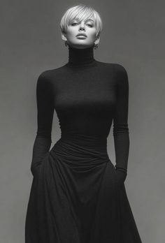 Woman with short blonde hair wearing a black turtleneck dress in a studio