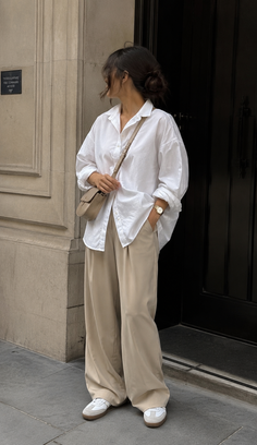 Woman in a white shirt and wide leg pants with a crossbody bag outdoors
