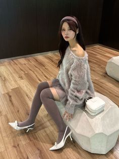 Woman in an off-shoulder sweater and thigh-high socks sitting indoors