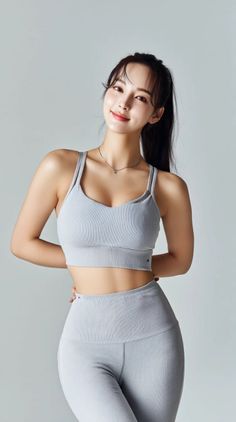 Woman in light gray sportswear with a ponytail posing in a studio
