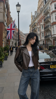 Woman in a brown leather jacket and jeans on a city street