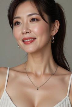 Woman with a ponytail and hoop earrings smiling in a white top