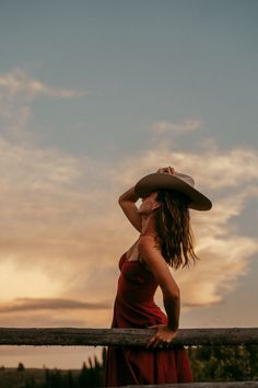 Woman in a red dress and cowboy hat at sunset