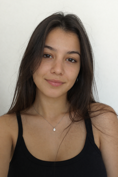Young woman with long dark hair wearing a black tank top and silver necklace