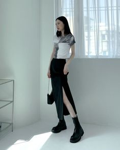 Woman in a black and white top and a black slit skirt with boots indoors