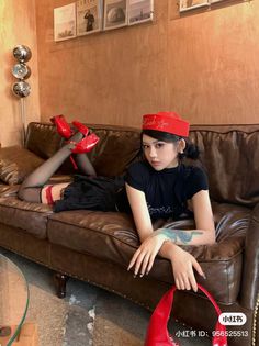 Woman in a red hat and black stockings posing on a brown leather couch