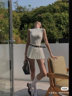 Woman in a white pleated skirt and sleeveless top posing outdoors
