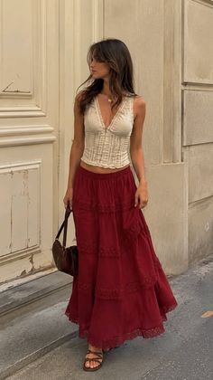 Woman with long hair wearing a red tiered skirt and a sleeveless top outdoors
