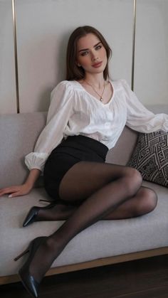 Woman in a white blouse and black skirt sitting on a sofa