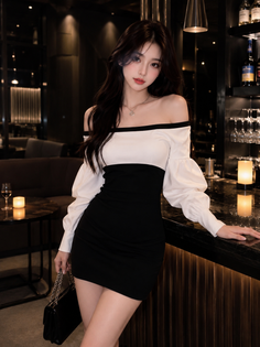 Woman in a black and white off-shoulder dress in a dimly lit nightclub