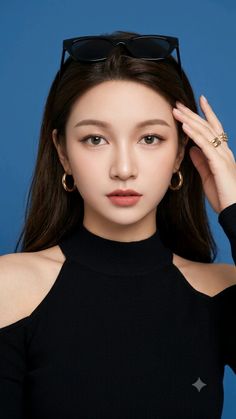 Woman with long hair and sunglasses on her head, wearing a black top and gold jewelry