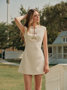 Woman in a white mini dress posing outdoors with her hand behind her head