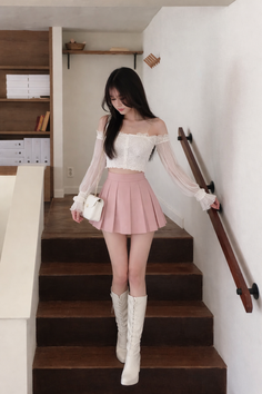 Woman in an off-shoulder top and pink pleated skirt walking down stairs
