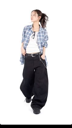 Woman in a plaid shirt and baggy pants with a ponytail and glasses