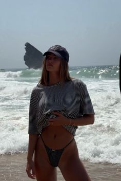 Woman in a striped shirt and polka dot bikini on a beach with ocean waves