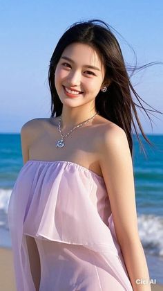 Smiling woman with long dark hair wearing a light purple strapless top at the beach