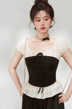Woman in a black and white polka dot top with a pearl necklace and bow details