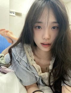 Woman with long dark hair wearing a blue top with lace trim, lying down