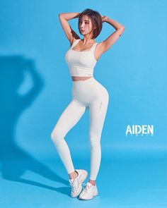Woman in white athletic wear posing against a blue background