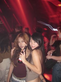 Two women with long hair in a nightclub with red lighting and motion blur