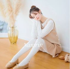 Woman in a brown dress and white tights sitting on a wooden floor