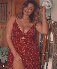 Woman in a red polka dot dress with cleavage and exposed leg indoors