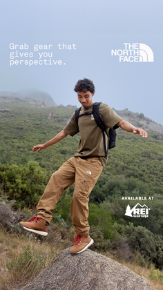 Man in hiking gear balancing on a rock outdoors