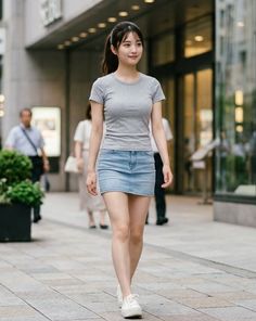 Woman in a gray t-shirt and denim skirt walking on a city street