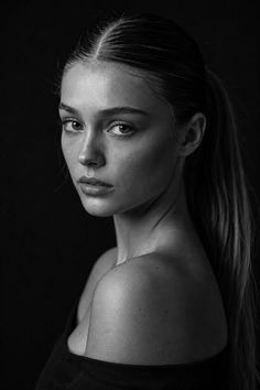 Black and white portrait of a woman with a ponytail and exposed shoulders