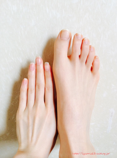 A hand and a bare foot with natural nails on a light surface