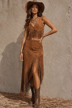 Woman in a brown fringe outfit and cowboy hat posing outdoors