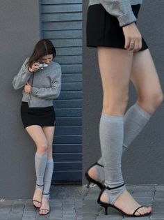 Woman in a grey sweater and black mini skirt with leg warmers and high heels