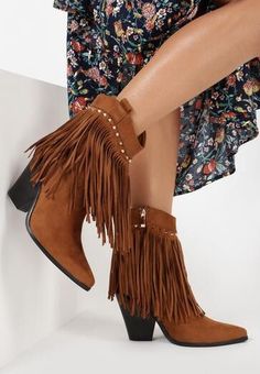 Close up of a person wearing brown fringe ankle boots and a floral dress