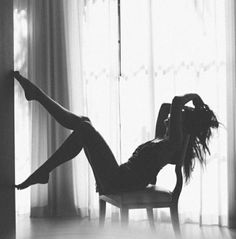 Woman in silhouette posing on a chair against a bright window