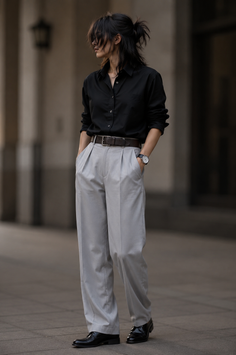 Person in a black shirt and light gray pants with a messy bun outdoors