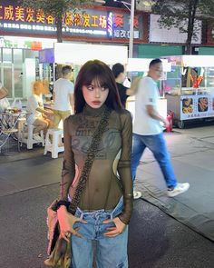 Woman in a sheer top and jeans on a street at night