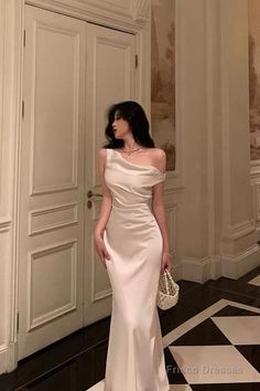 Woman in a white elegant dress holding a pearl bag indoors