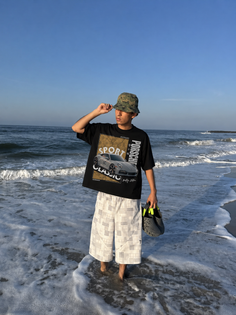 Man in a bucket hat and t-shirt standing in the ocean surf