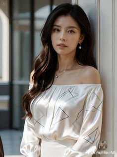 Woman with long dark hair wearing an off-shoulder top and pearl jewelry