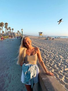 Blonde woman on a beach boardwalk at golden hour with a denim jacket