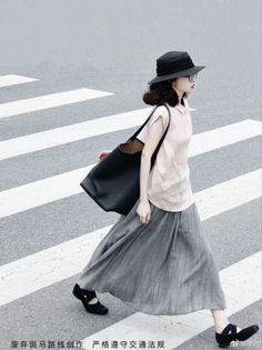 Woman in a black hat and long skirt crossing a street